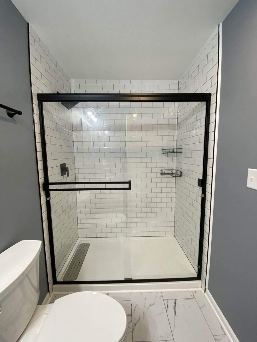 Glass-enclosed walk-in shower with white subway tiles and a sleek black frame by Clear Contractors in Northwest Indiana