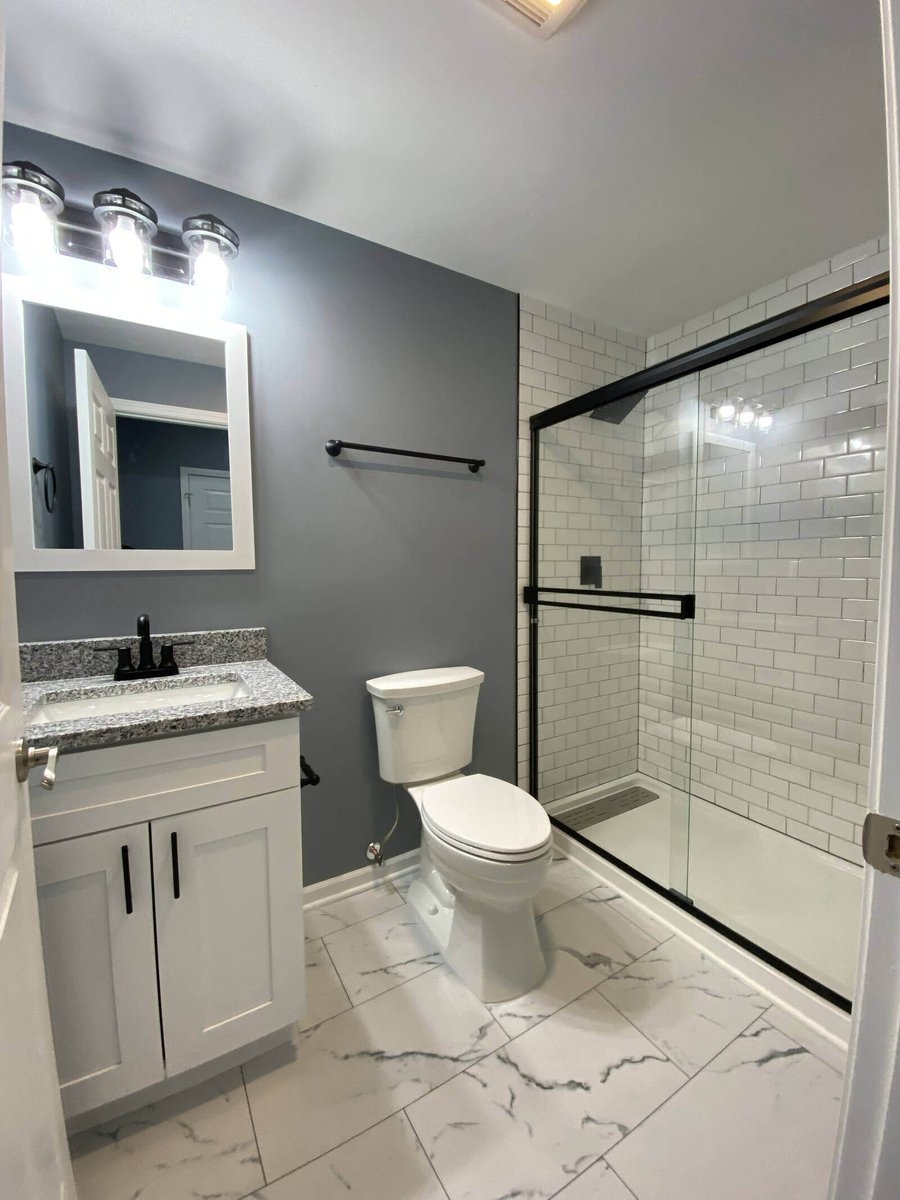 Modern bathroom remodel with a granite countertop vanity, white cabinets, and gray walls in Northwest Indiana by Clear Contractors