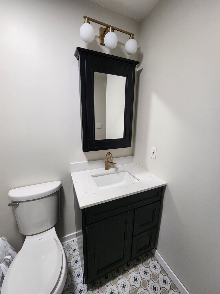 Bathroom remodel showcasing a black vanity with gold fixtures, completed by Clear Contractors in Northwest Indiana