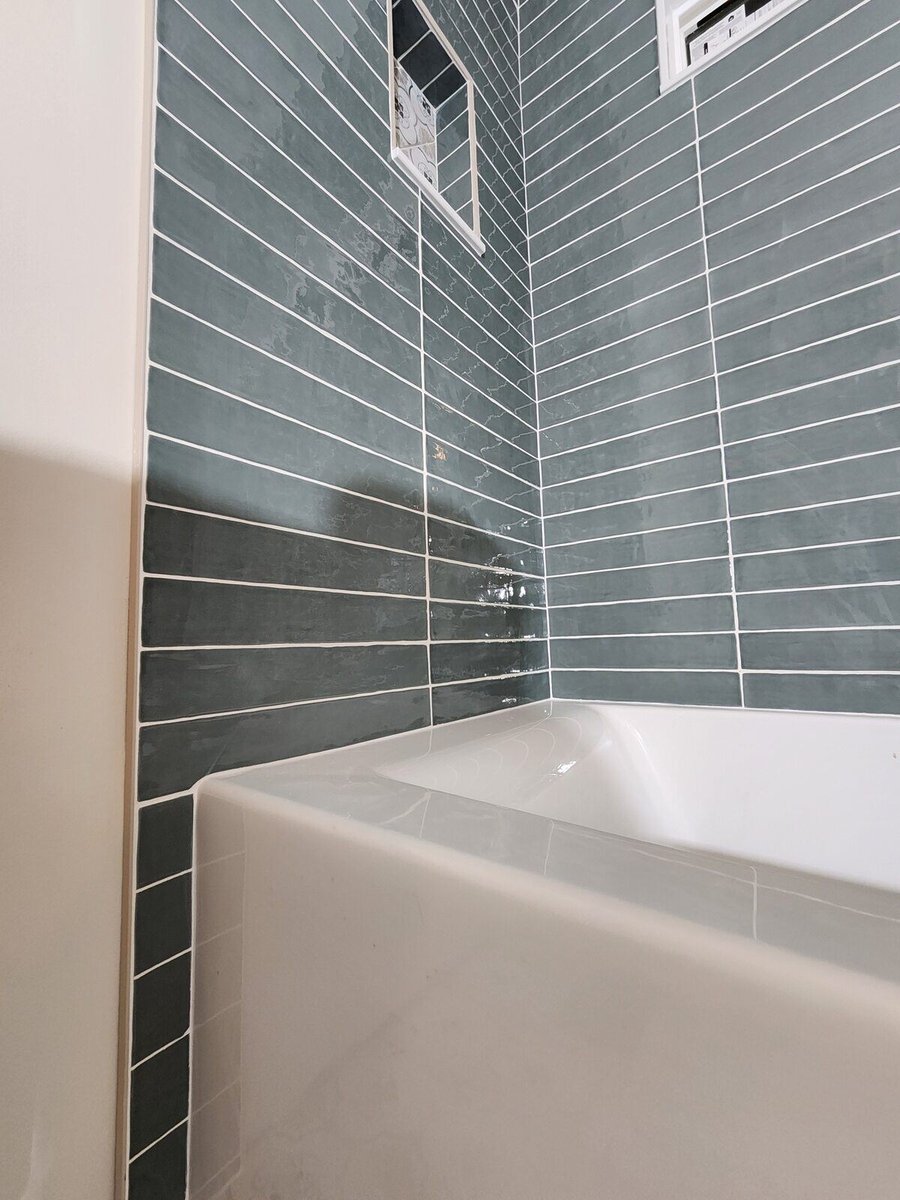 Close-up of green subway tiles and a bathtub in a Northwest Indiana bathroom remodel by Clear Contractors