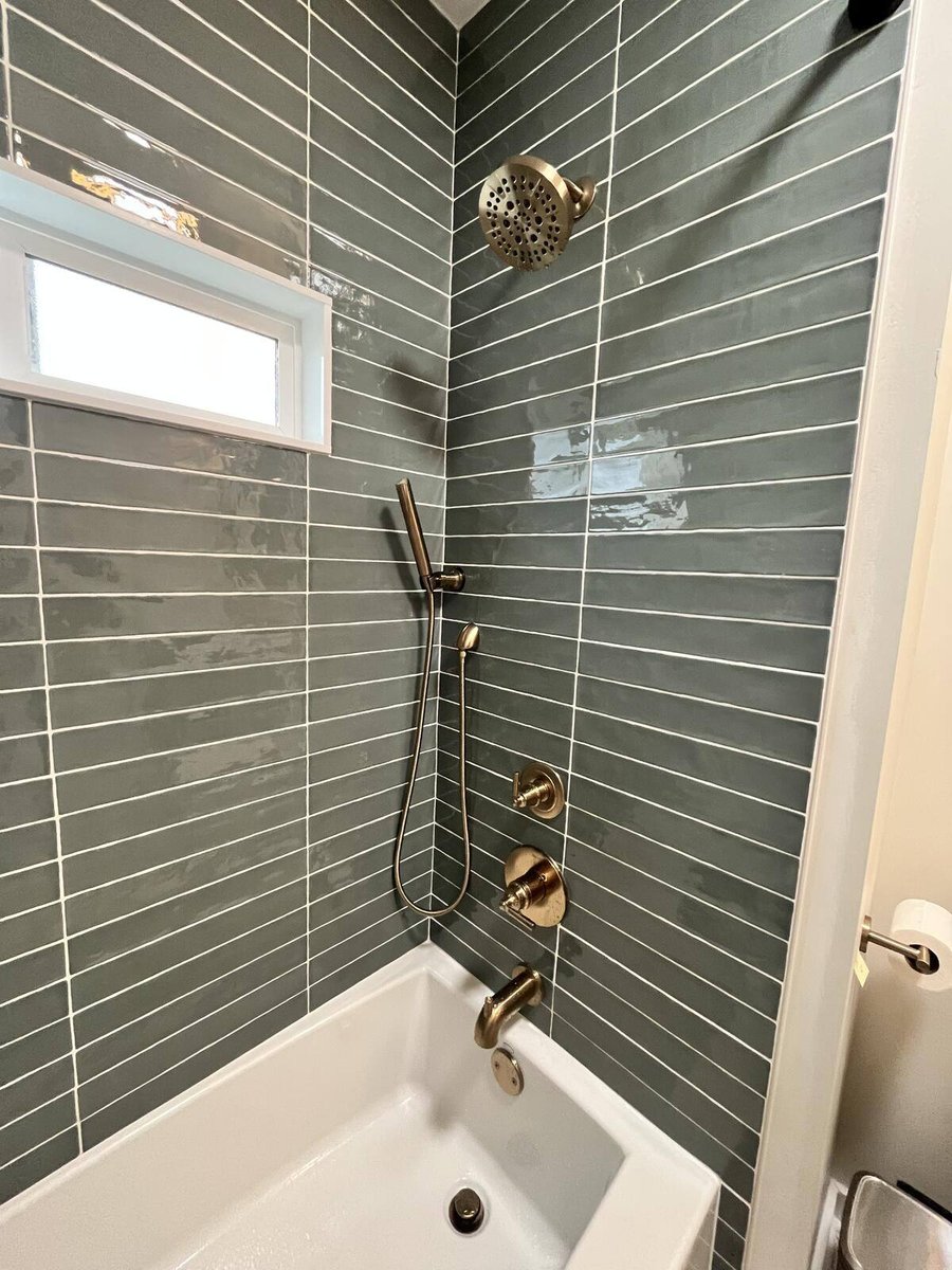 Stylish bathroom remodel featuring green subway tiles and gold hardware by Clear Contractors in Northwest Indiana