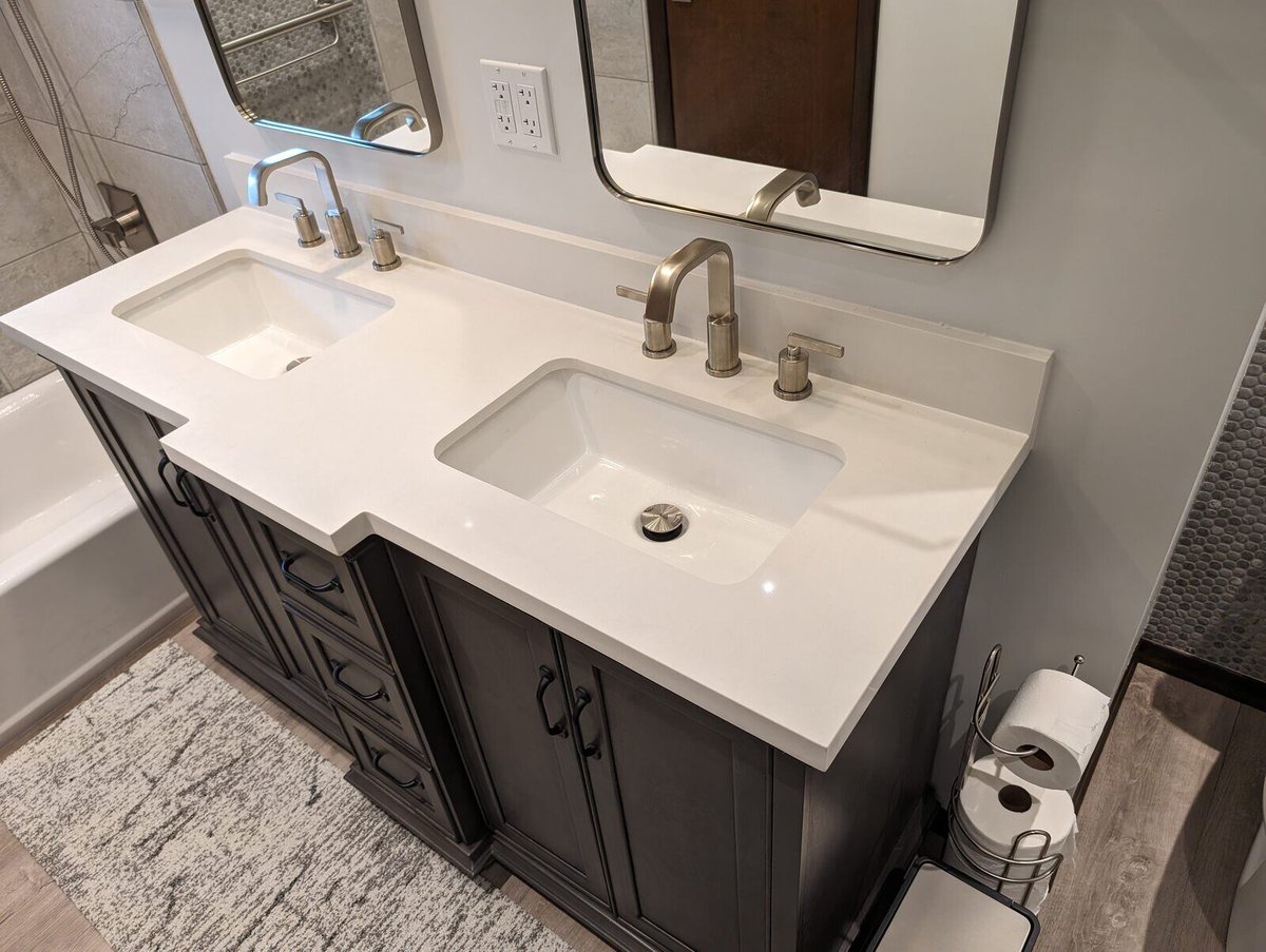 Dual bathroom sinks with sleek fixtures and dark cabinetry in a remodel by Clear Contractors in Northwest Indiana