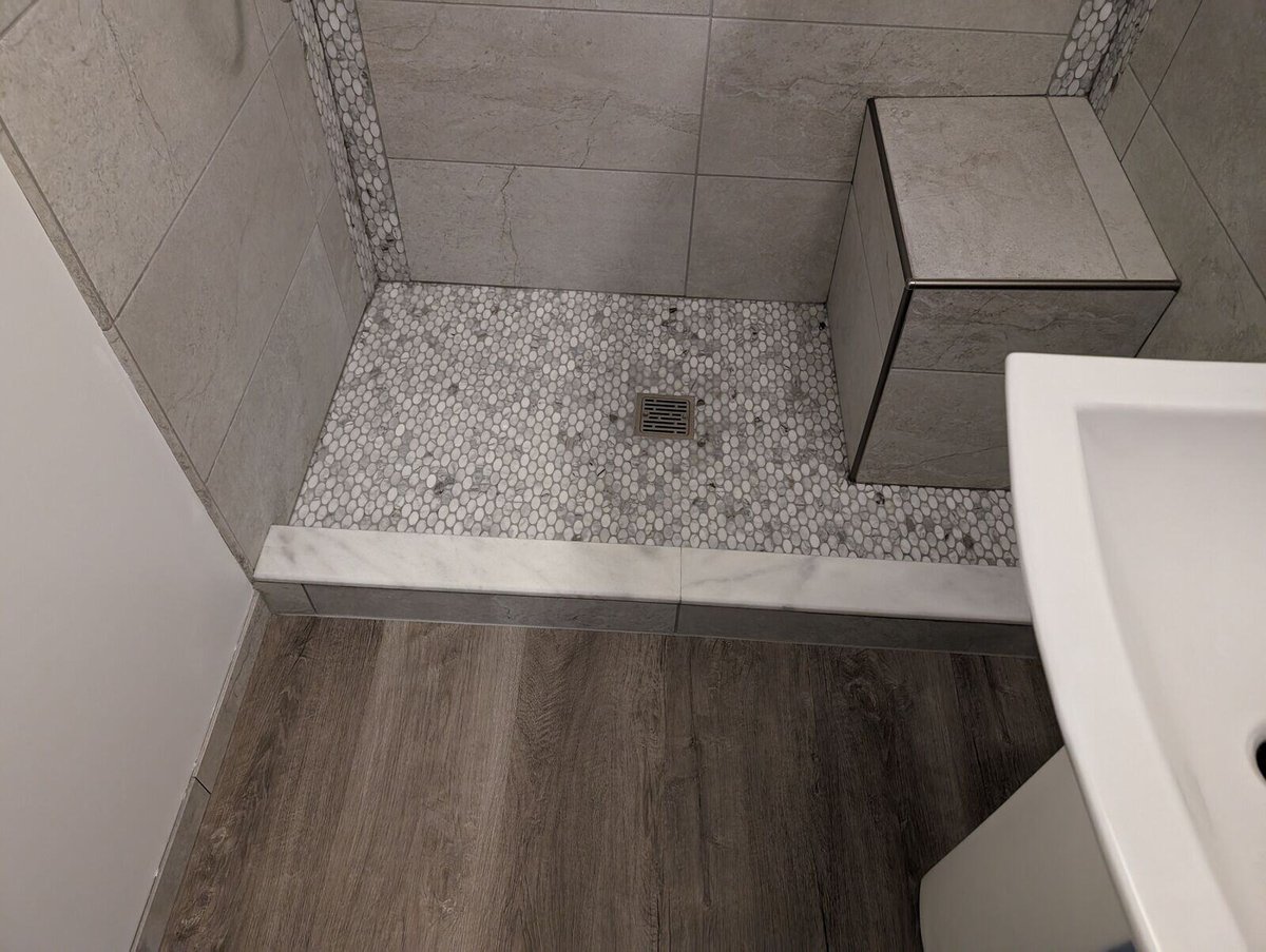 Remodeled bathroom shower featuring textured tile and a bench seat by Clear Contractors in Northwest Indiana