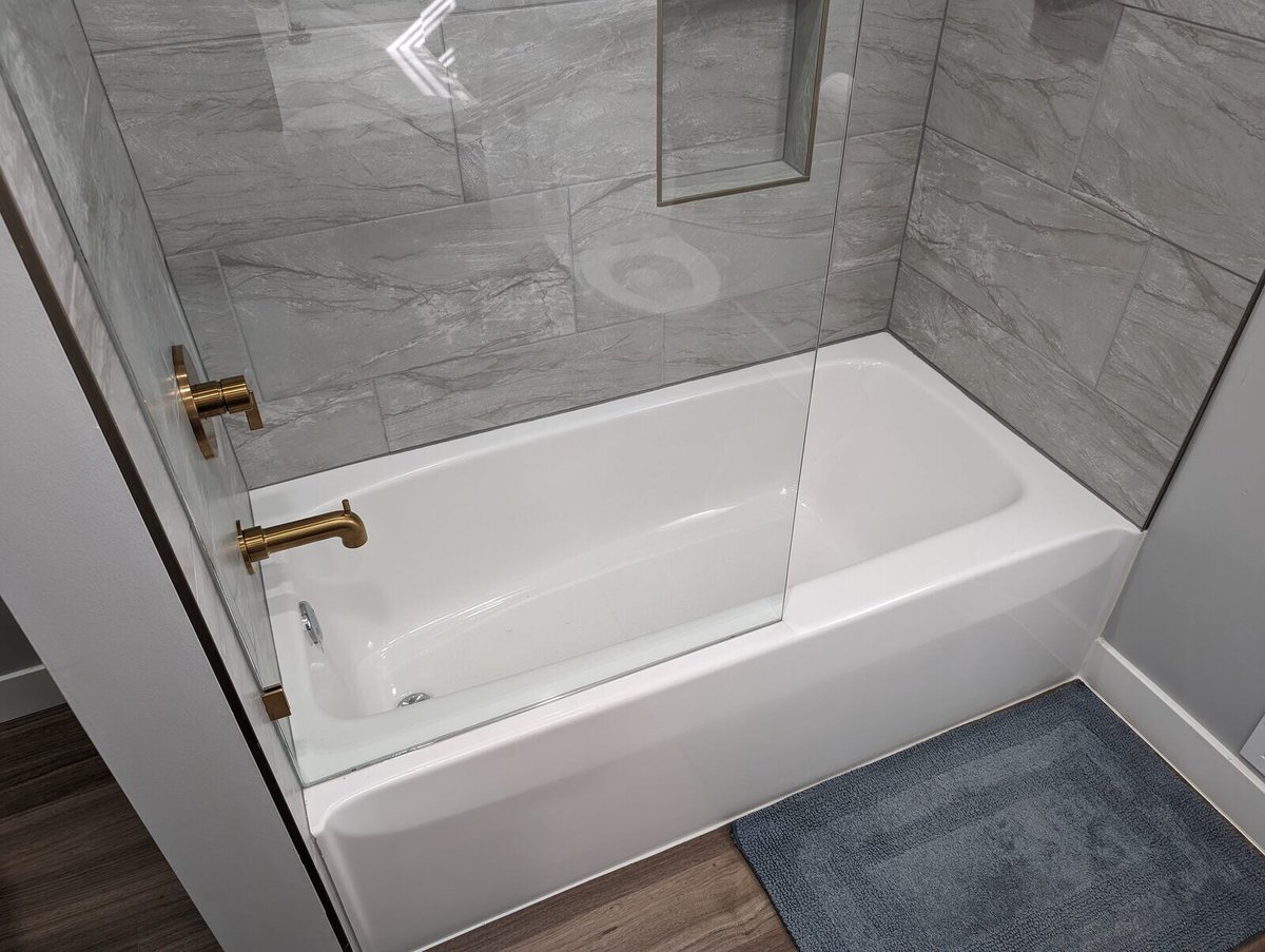 Bathroom remodel with a white bathtub and sleek gray marble tile surround by Clear Contractors in Northwest Indiana