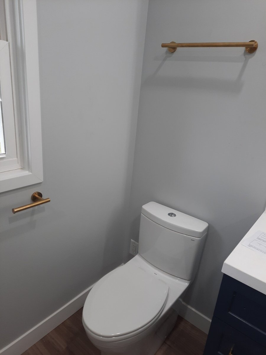 Bathroom with a white toilet, gold towel rack above, and a matching gold hand towel bar near the window, remodeled by Clear Contractors in Northwest Indiana.jpg