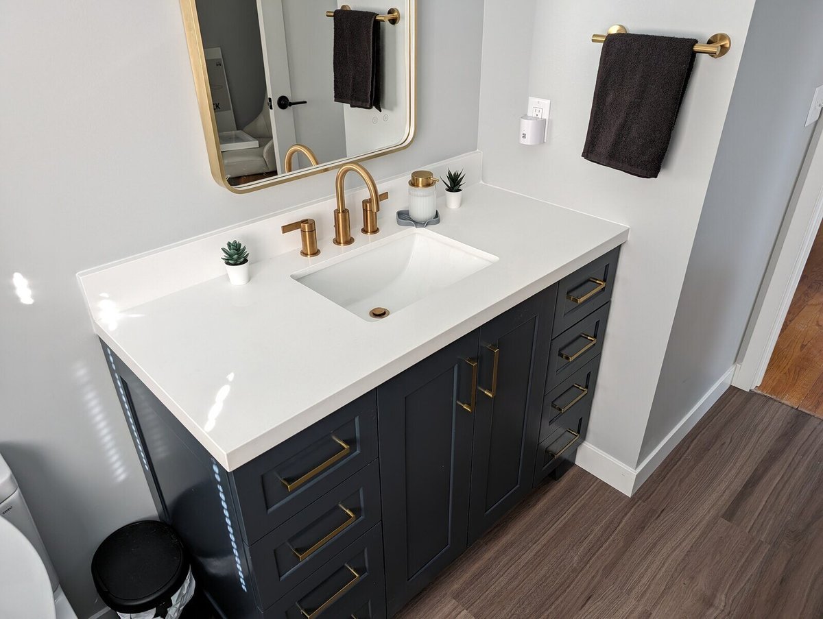 Elegant bathroom vanity with gold fixtures and a navy-blue base by Clear Contractors in Northwest Indiana