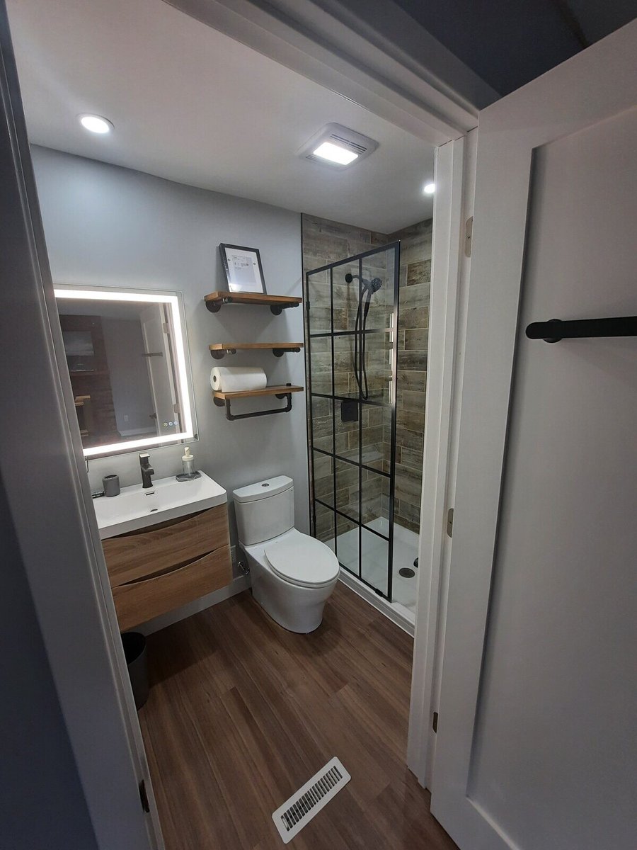 Full bathroom view with a floating vanity, toilet, and a tiled shower featuring a glass enclosure, remodeled by Clear Contractors in Northwest Indiana.jpg