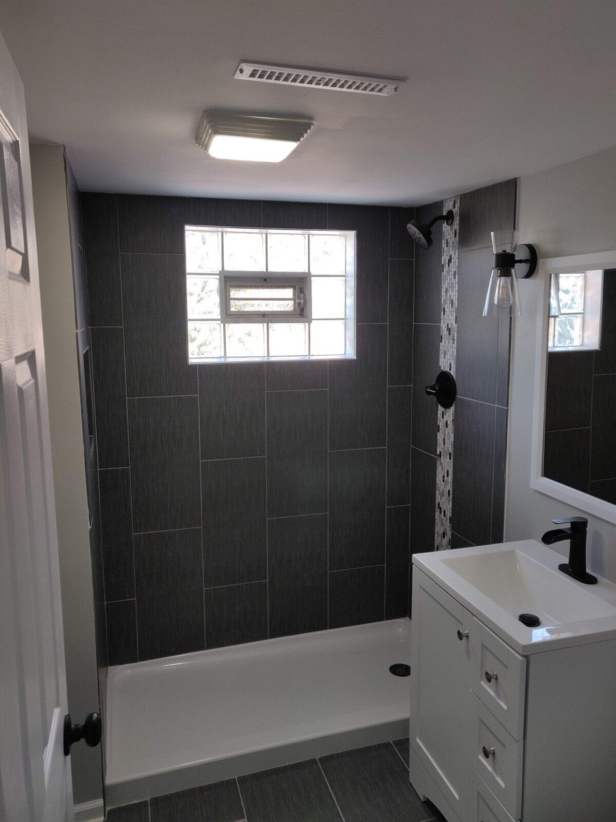 Modern bathroom remodel with gray tiled shower and white vanity by Clear Contractors in Northwest Indiana